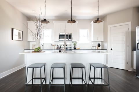 Kitchen features an island with barstool seats.