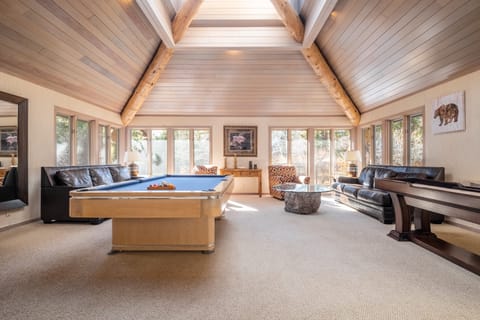 Spacious game room with vaulted ceilings, a pool table, and a shuffleboard.