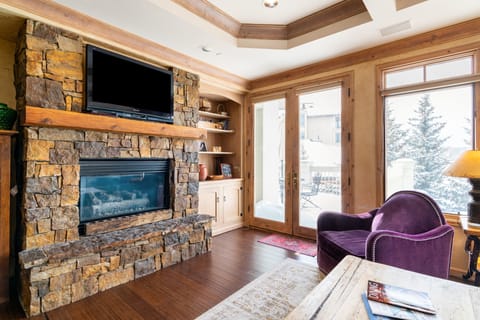 Cozy living room features a fireplace, TV, and balcony access.