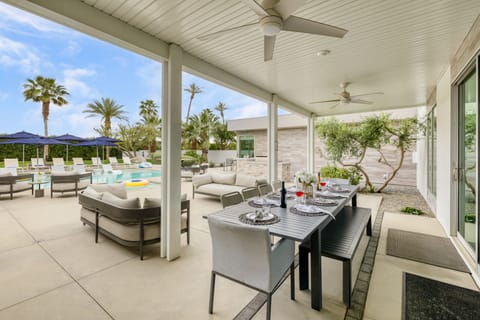 Poolside patio features an outdoor living area and a covered dining table.