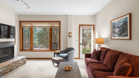 Cozy living room with forest views and warm, lodge-style seating.