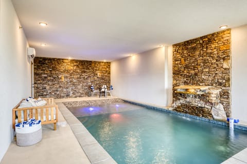 Indoor heated concrete pool features beach entry.