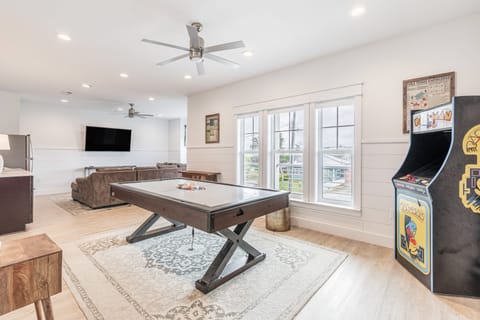 Recreation room features billiards, an arcade game, and a sitting area.