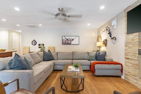 Living area with TV, ceiling fan and plush sofa.