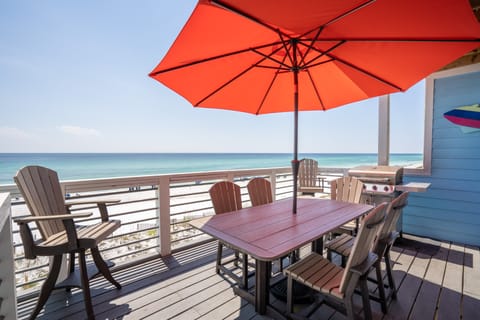 Second-level deck features a BBQ/grill and a shaded outdoor dining table.