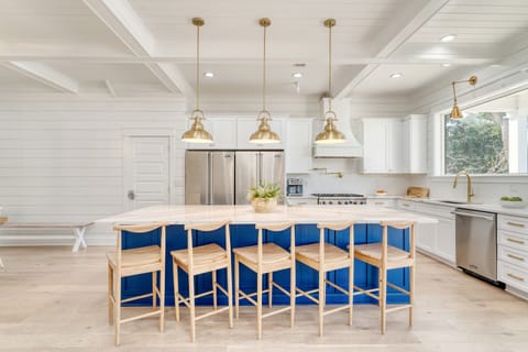 Large kitchen with double fridges and a large counter with barstool seating.