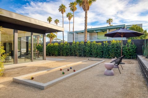 Bocce ball court and patio with an outdoor dining table and BBQ grill.