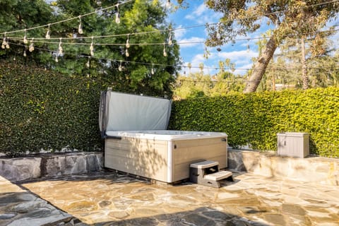 Courtyard hot tub surrounded by greenery and lighting.