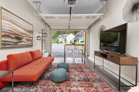 Converted garage lounge at Sweetgum features a sleep sofa, TV, and table.