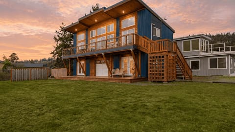 Golden-hour skies, warm cabin lights, and a spacious lawn set the scene for a peaceful Whidbey Island escape.