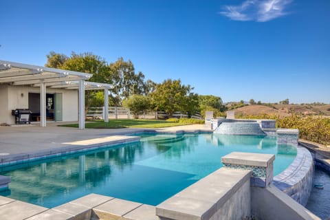 A large swimming pool with a waterfall in the backyard.