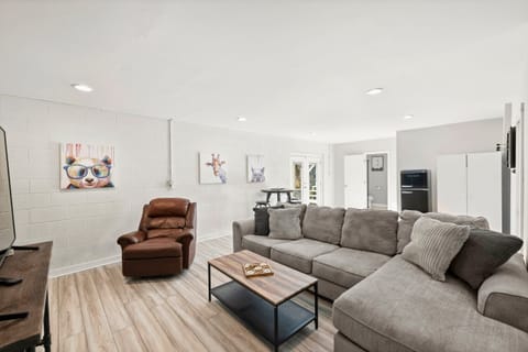 Lower level game room with couch, chair, tv, darts & high top bar table.