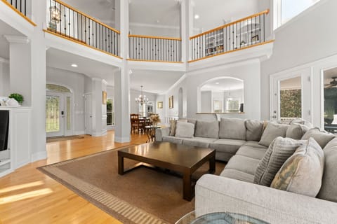 Main level living room with vaulter ceilings, large sectional, TV and deck access.