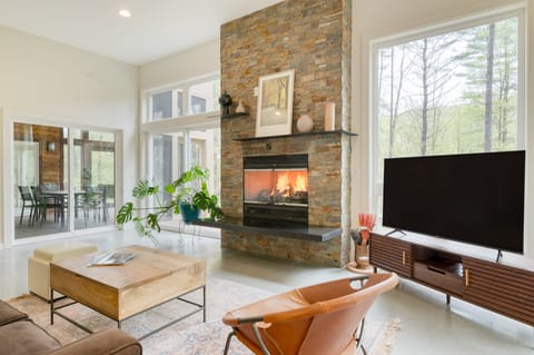 Bright, open living room with a large fireplace, plush seating, and TV.