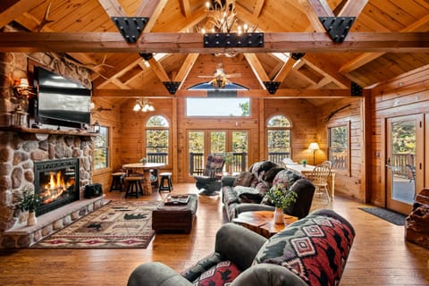 Cozy cabin living area with vaulted ceiling and stone fireplace.