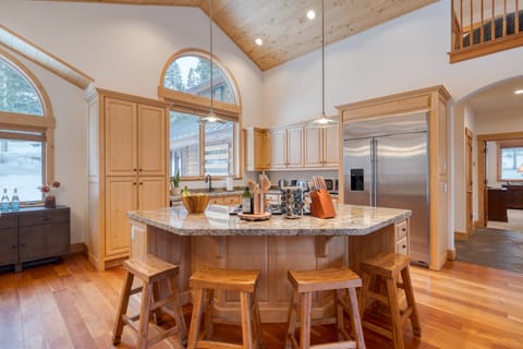Your gourmet kitchen features a large refrigerator and a central island table.