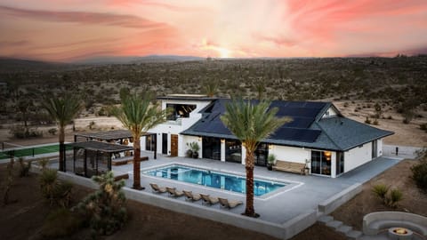 Stunning contemporary home with a private pool, palm trees, and sleek architecture set against the desert landscape.