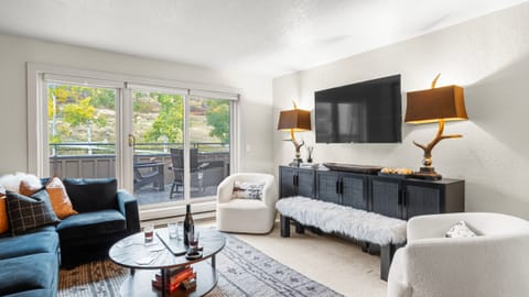 Cozy living room with comfortable seating, TV, fireplace and deck access.