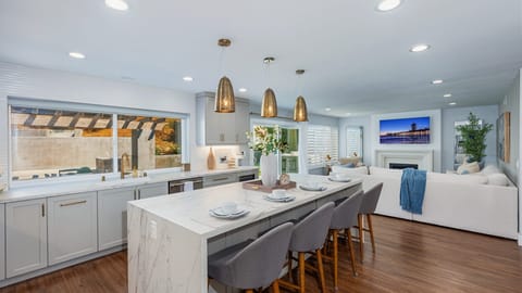 Open-concept kitchen with barstool seating, waterfall counter island, and pendant lights.