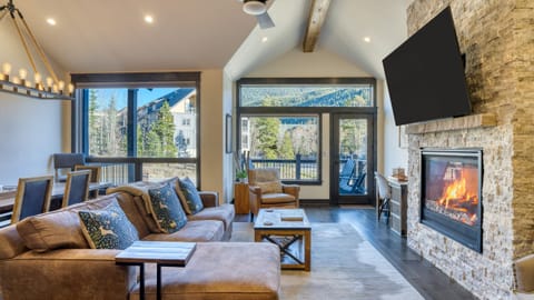 Living room with fireplace, TV, and comfy sofa with access to the balcony.