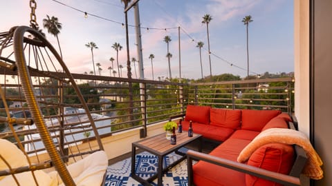 Balcony lounge area with red outdoor sofas and city views at sunset.