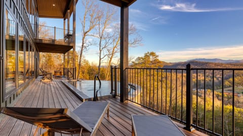 Terrace-level infinity pool and loungers overlooking sweeping Smoky Mountain vistas bathed in golden hour light.