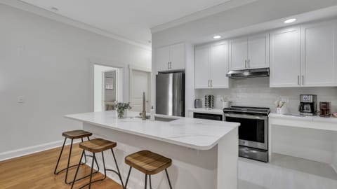 Contemporary kitchen with island seating, stainless steel appliances, and white cabinetry.