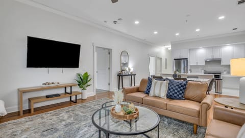 Bright living room featuring modern seating, a smart TV, and a ceiling fan.