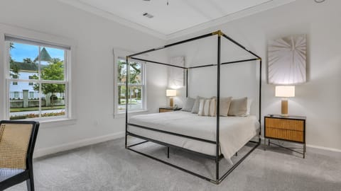 Primary bedroom featuring king bed, a canopy bed, nightstands, and large windows.