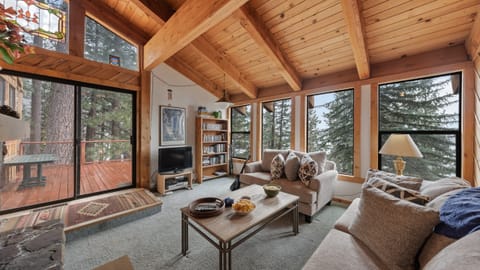 Cozy lakeview living room with vaulted wood ceilings, picture windows, and direct deck access.