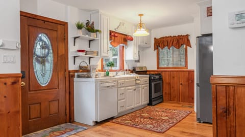 Kitchen with white cabinets, light wood trim, a stainless steel sink, and a patterned rug.