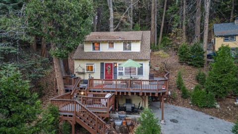 Exterior view of a cozy, elevated wooden cabin surrounded by trees, with a deck.