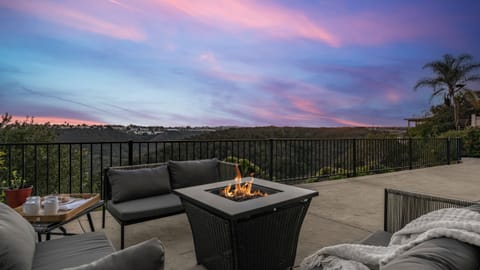 Outdoor patio with a fire pit table and seating, overlooking the scenic canyon view at sunset.