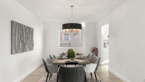 Formal dining area with a modern wood table, grey chairs, and a contemporary chandelier.