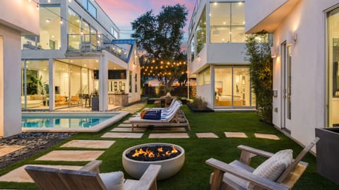 Shared outdoor retreat with a sleek pool, lounge chairs, and glowing string lights.