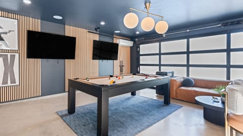 Game room with a modern pool table, lounge seating, and dual TVs—perfect for laid-back entertainment.