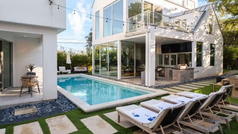 Shared outdoor retreat with a sleek pool, lounge chairs, and glowing string lights.