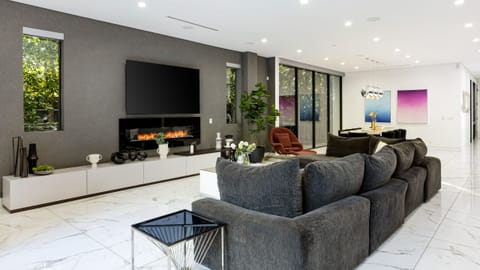 Sleek open-concept living room with_toggle fireplace, modern furnishings, and seamless indoor-outdoor flow.