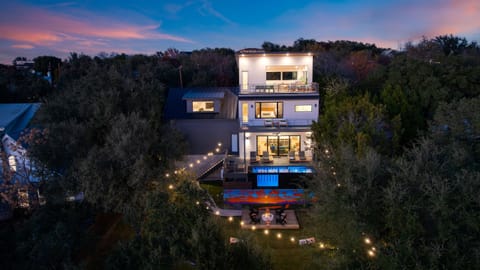 Austin nights shine at this multi-level retreat, with glowing decks, a private pool, and sunset views framed by the trees.