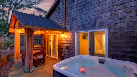 Cozy Oregon Coast retreat with private hot tub, covered patio, and warm evening glow.