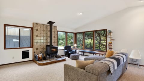Spacious living area featuring a wood-burning stove with decorative tile and large windows.