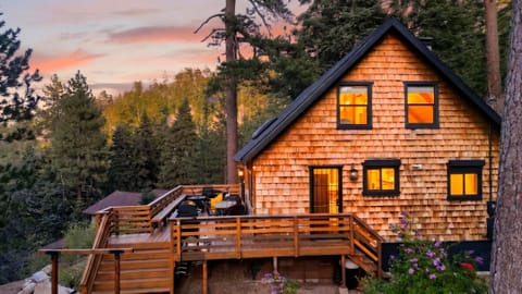 Stunning mountain architecture featuring classic cedar shingles and a spacious outdoor living area nestled in the forest.