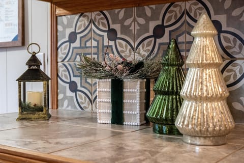 Festive décor with green and gold trees, a lantern, and a gift box centerpiece.