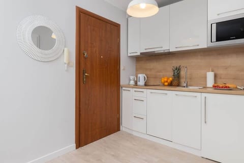 A full kitchen setup with white cabinetry, a wooden door, and coastal-themed decor, blending style and utility.






