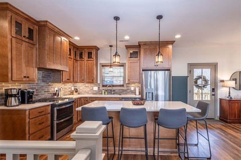 Modern kitchen with wood cabinetry, stainless steel appliances, and center island with bar seating.