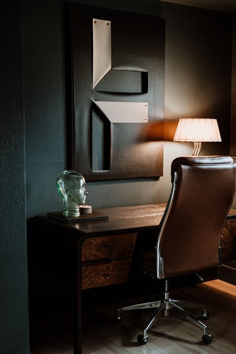 - Stylish dedicated workspace featuring a wood desk and ergonomic leather chair
- Artistic wall decor and a sculptural glass head add creative flair to your focus zone
- Ambient lamp lighting sets the mood for productivity or quiet reading moments