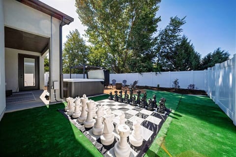 Checkmate under the sun: An expansive backyard chessboard awaits your next move, alongside a soothing hot tub for post-game relaxation
