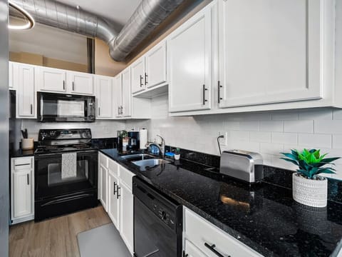 Sleek kitchen featuring granite countertops and modern black appliances   - White cabinets with chrome handles and clean subway tile backsplash   - Essentials like toaster, dishwasher, and coffee maker ready for use