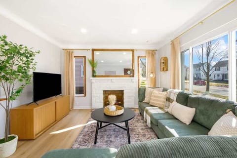 Bright living room w/ cozy seating, TV & large windows letting in plenty of natural light
