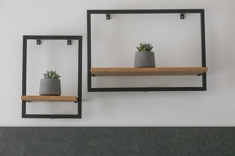 A decorative wall shelf with minimalist black frames and small plants, adding a stylish accent to the interior.


